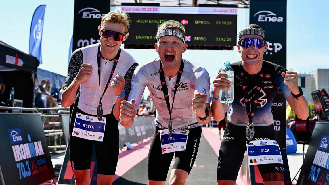 Trzech zawodników Enea Ironman cieszących się na mecie zawodów.