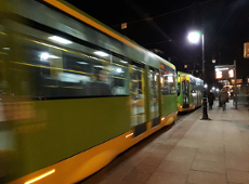 Widko z boku na jadący tramwaj w nocy Tramwaj koloru zielonego..