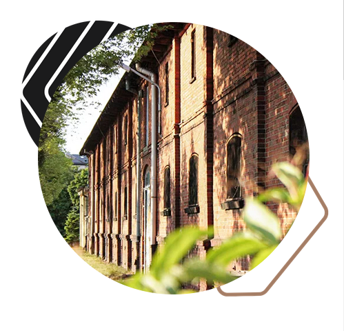 Budynek z czerwonej cegły, otoczony zielenią.