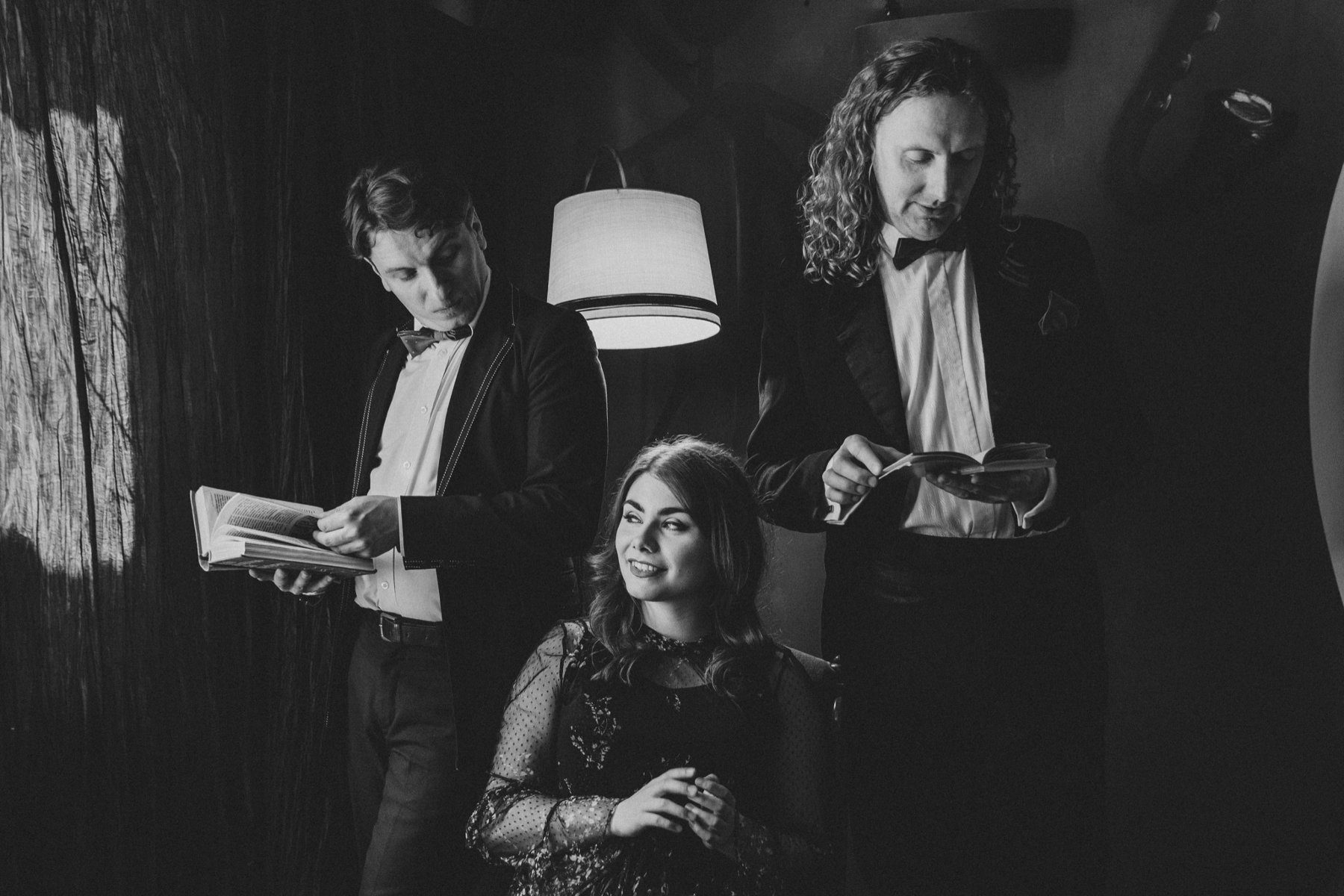 Dwójka mężczyzn trzyma książki. Między nimi siedzi kobieta.