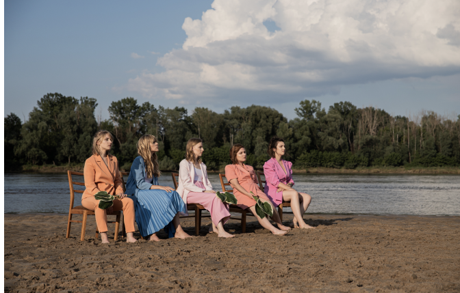 Na zdjęciu członkinie zespołu siedzące na krzesłach na plaży.