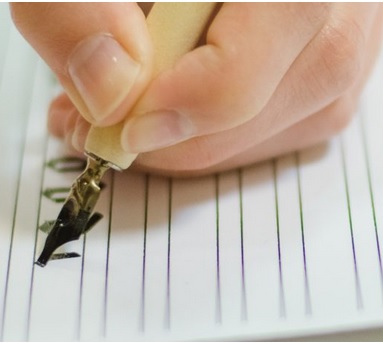 Zdjęcie dłoni z wiecznym piórem w trakcie kalilgrafowania.