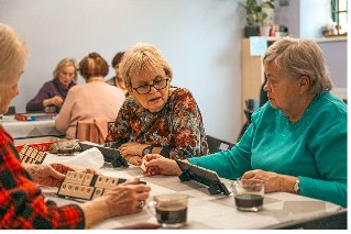 Grupa kobiet gra w Rummikub przy kawie.