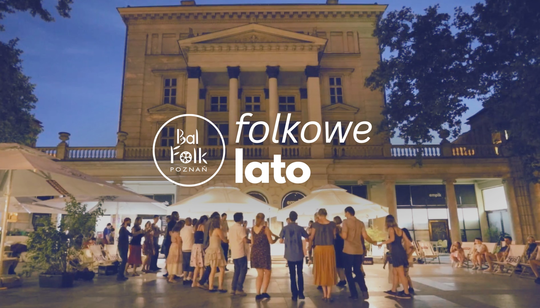 Grupa ludzi na placu Wolności zebrana w kole, są zwróceni tyłem do obiektywu. Z boku po prawej kilka osób siedzi na leżakach.