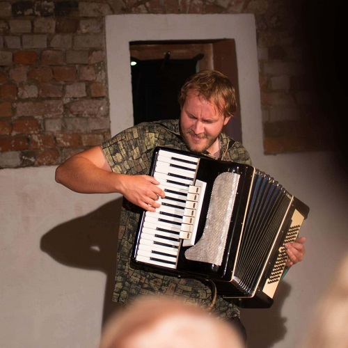 Na zdjęciu mężczyzna grający na akordeonie.