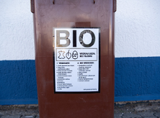 Zdjęcie przedstawia brązowy pojemnik na bio odpady na tle biało-niebieskiej ściany.