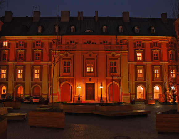 Zdjęcie przedstawia budynek urzędu rozświetlony na czerowno. Zdjęcie zrobiono o zmroku.