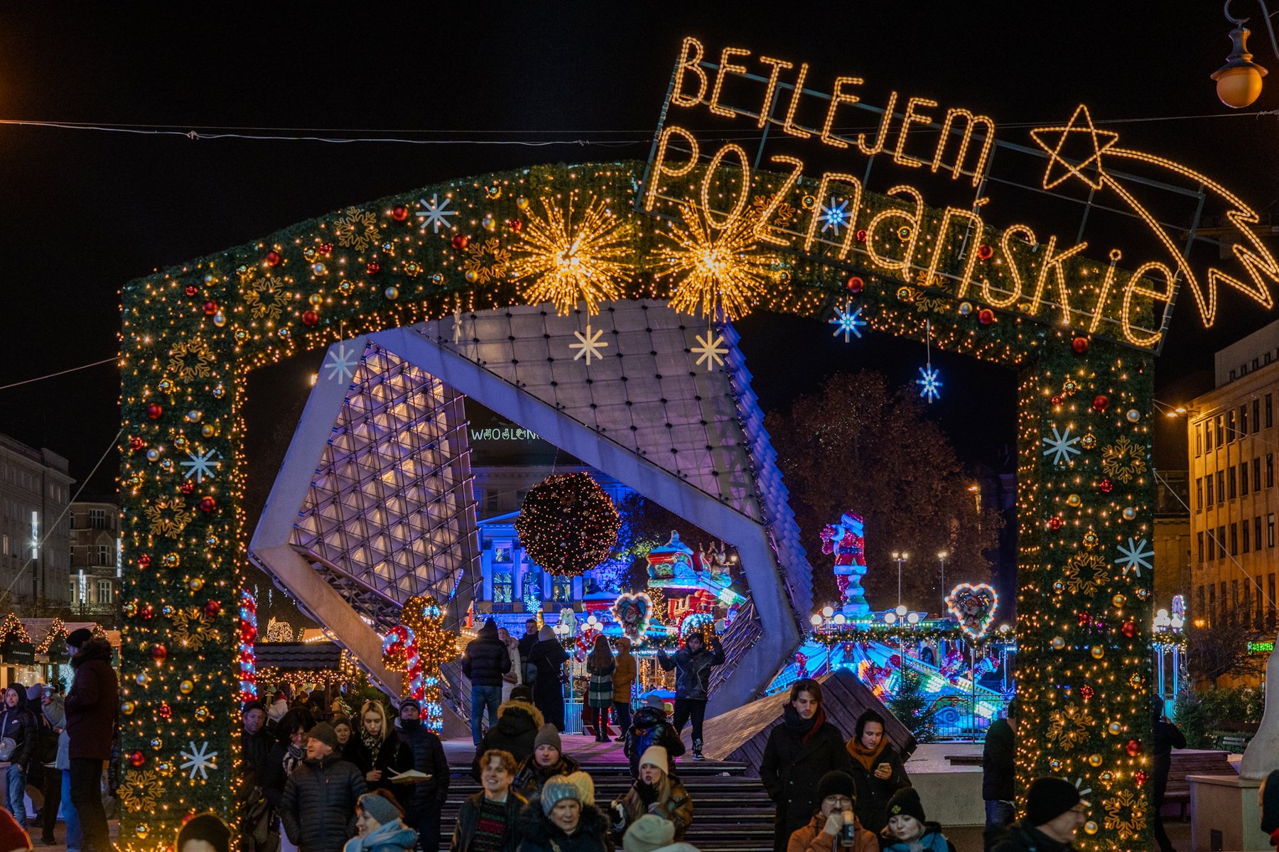 Zdjęcie przedstawia drewniane domki wystawców na Starym Rynku, świąteczne ozdoby oraz otaczające rynek budynki.