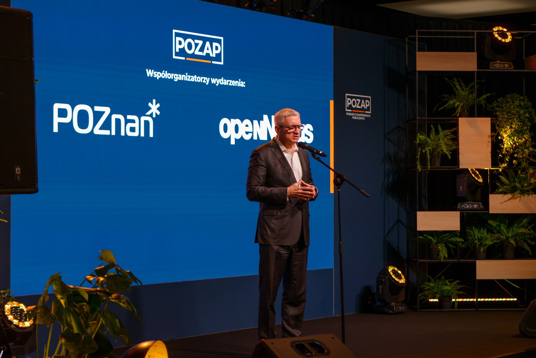 Zdjęcie przedstawia dwie kobiety mówiące do mikrofonu na scenie.