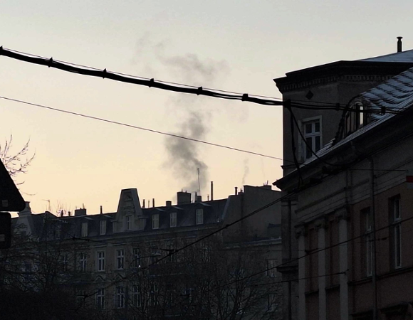 Zdjęcie przedstawia dymiący komin i budynki.