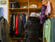 Zdjęcie przedstawia kobietę przeglądającą wieszaki z ubraniami.