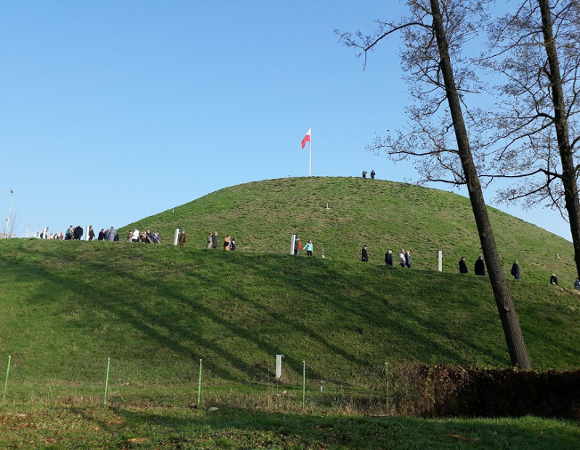 Zdjęcie przedstawia Kopiec Wolności, na który wchodzą ludzie.