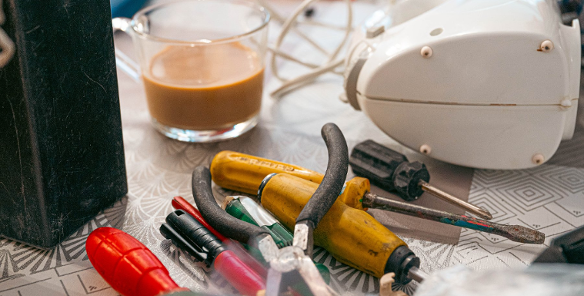 Zdjęcie przedstawia leżące na stole narzędzia i mikser oraz szklankę z kawą.