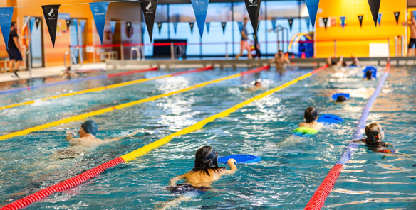 Zdjęcie przedstawia ludzi pływających w basenie.