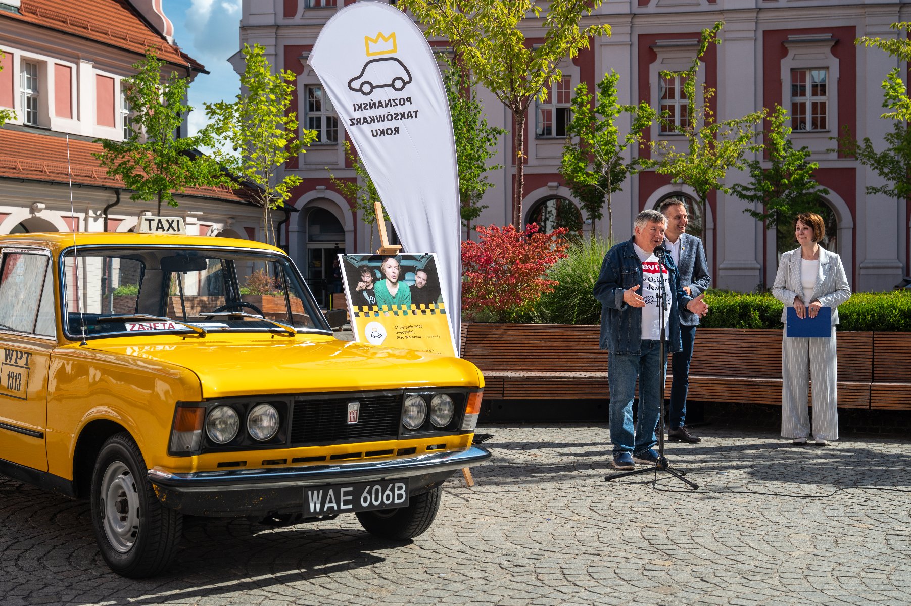 Zdjęcie przedstawia mężczyznę stojącego obok zółtej taksówki.