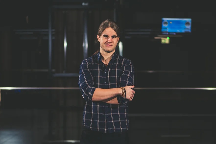 Zdjęcie przedstawia młodego mężczyznę w pomieszczeniu.