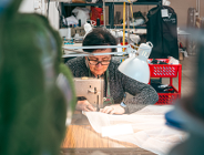 Zdjęcie przedstawia pracującą na maszynie do szycia w zakładzie krawieckim.