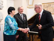 Zdjęcie przedstawia prezydenta ściskającego rękę kobiecie. Obok stoi mężczyzna.