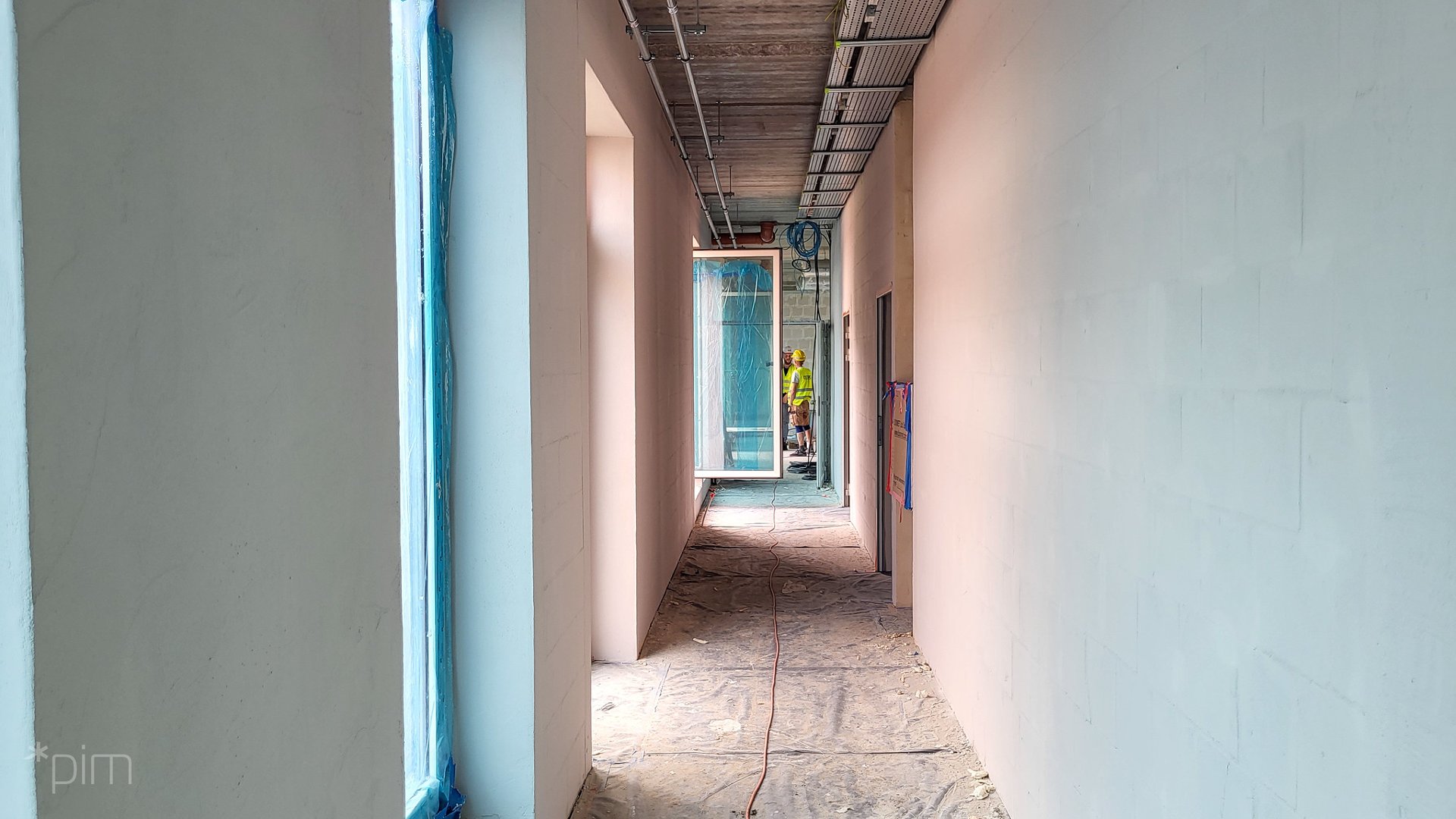 Zdjęcie przedstawia remontowany korytarz i robotników.