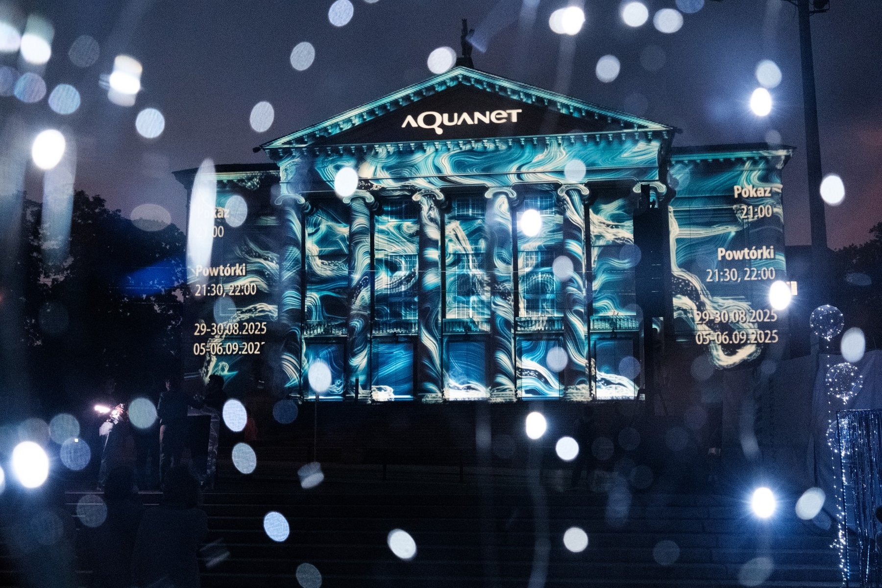 Zdjęcie przedstawia rozświetloną fasadę teatru w nocy.