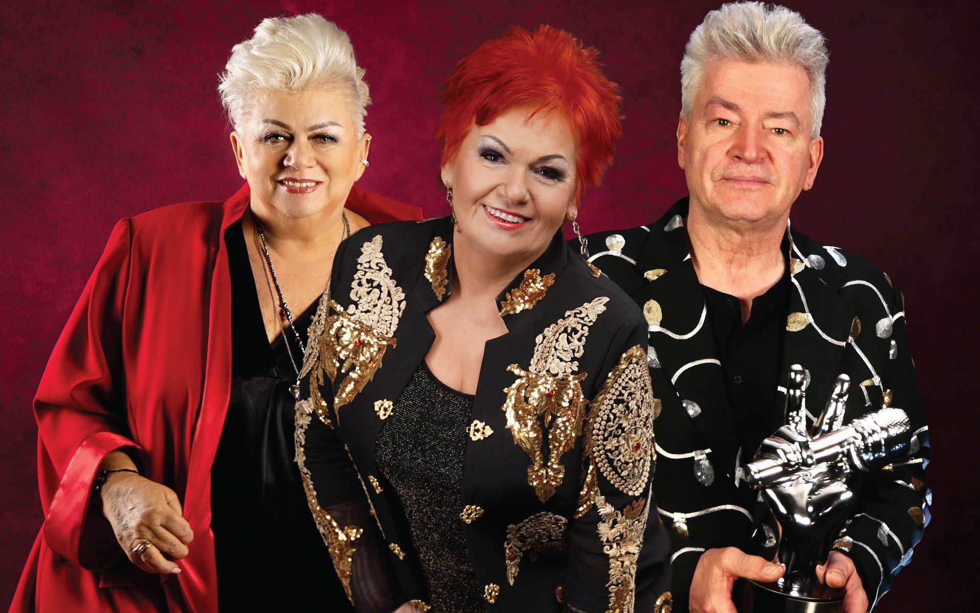 Zdjęcie przedstawia sylwetki trzech uczestników programu "The Voice Senior" na bordowym tle.