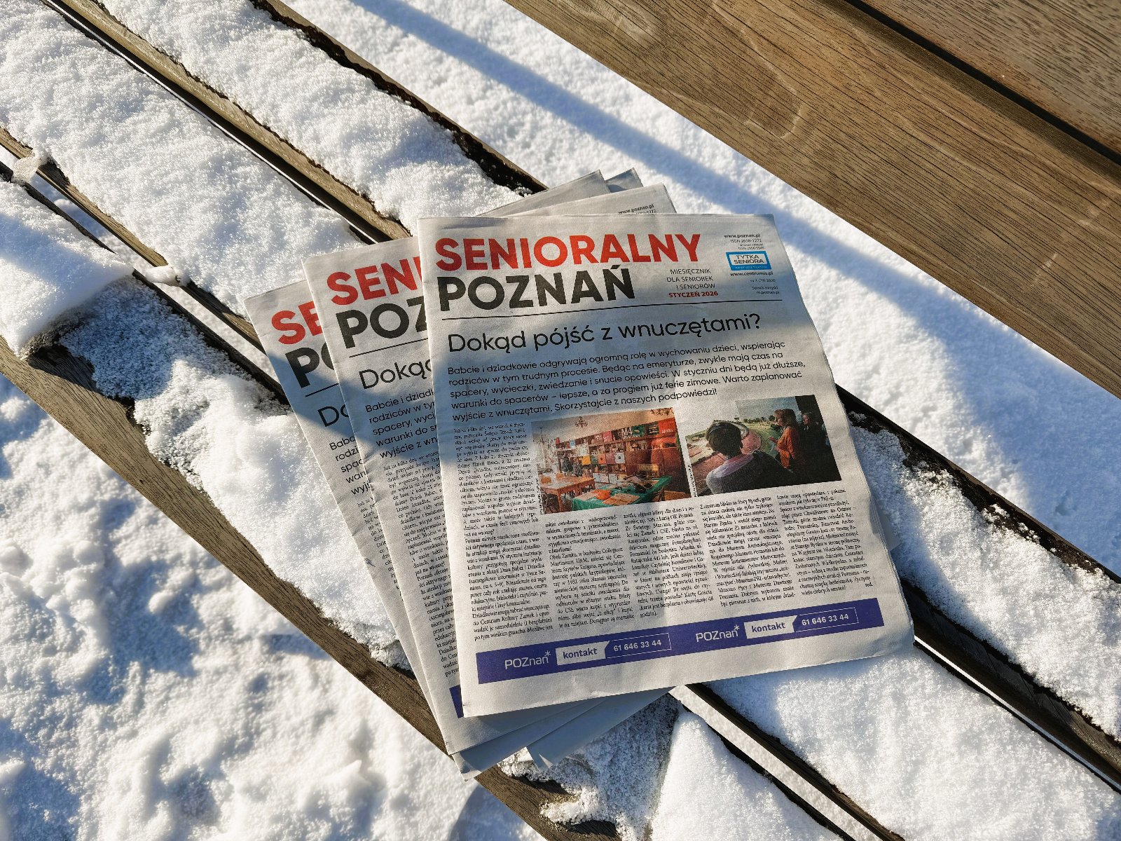 Zdjęcie przedstawia zaśnieżoną ławkę na której leży aktualne, styczniowe wydanie gazety "Senioralny Poznań"