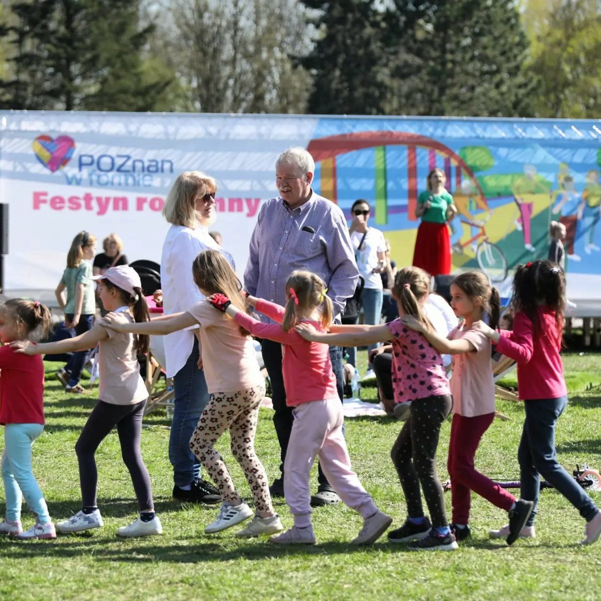 Zdjęcie przedstawia kilka osób, dzieci, mężczyznę oraz kobietę bawiących się na festynie