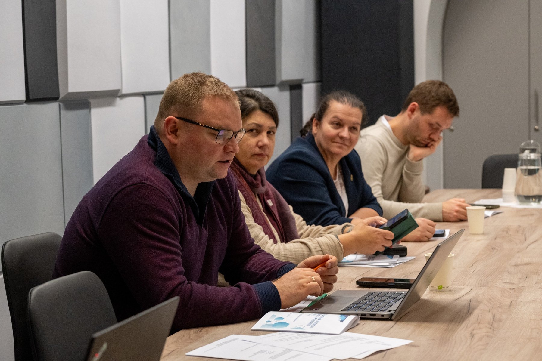 Zdjęcie z komisji. Radni siedzą przy stole.