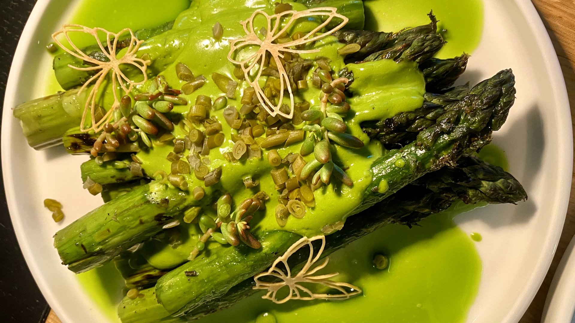 Zielone szparagi w zielonym sosie z artystycznymi dekoracjami - jadalne motylki.