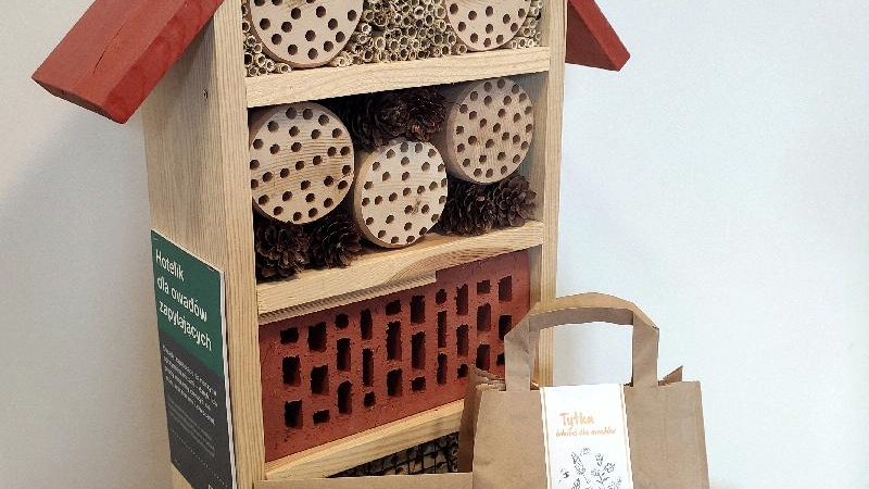 Galeria zdjęć przedstawia domek dla owadów wykonany z drewna, szyszek, gałęzi oraz pakiety z nasionami w zaszetkach.