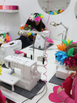 Foto:Dzieci w wiankach papierowych na głowach przy maszynach do szycia