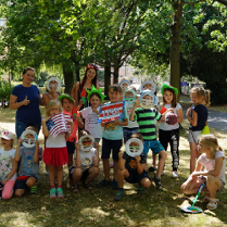 Dzieci z opiekunką podczas półkolonii, trzymające gadżety.