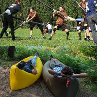 grupa chłopców walczy na trawie, 2 odpoczywa w canoe.