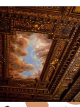 Widok zdobionego, rzeźbionego, drewnianego sufitu z malunkiem nieba i chmurami.