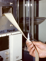 Z maszyny wychodzi taśma paieru z wydrukie. Taśmę trzyma dłoń najprawdopodobniej lekarza.