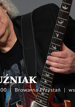 Zdjęcie Piotra Kuźniaka trzymającego gitarę na szarym tle. Na froncie napisy. Szczegóły dotyczące wydarzenia zawarte w treści artykułu.