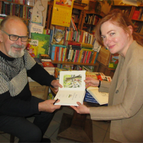 Juliusz Kubel i kobieta trzymaja książkę. Dookoła półki z książkami.