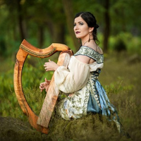 Na zdjęciu Barbara Karlik z harfą na łące, w pięknej sukni