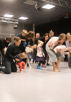 Dorośli i dzieci w ruchu w jasno oświetlonym pomieszczeniu.