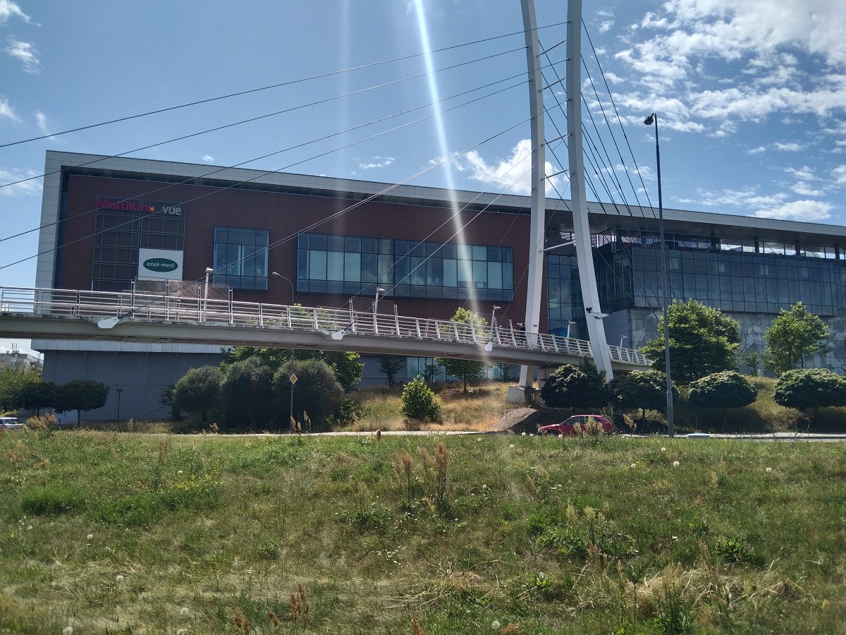 kładka pieszo rowerowa nad jezdnią, za nia budynek galerii handlowej - więcej w artykule