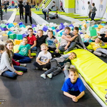 Baner: dzieci siedzą i leżą na trampolinach. w głębi miękkie kostki z pianki.