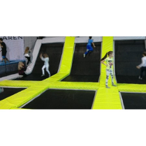 Dzieci na trampolinach oddzielonych żółtymi materacami.