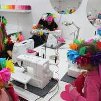 Foto:Dzieci w wiankach papierowych na głowach przy maszynach do szycia