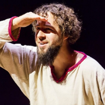 Karawany Opowieści: uśmiechnięty, ubrany w białą płócienną koszulę aktor wypatruje czegoś w oddali.