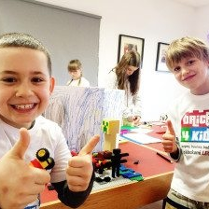 Uśmiechnięte dzieci. Na stole klocki lego.