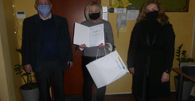 Zdjęcie przedstawia osoby trzymające dyplom i statuetkę.
