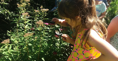 fotografia przedstawia dzieci używające lupy to obserwowania rośliny