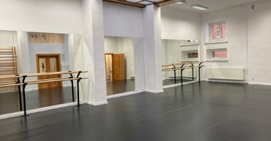 zdjęcie przedstawia wnętrze sali tanecznej, na ścianach wiszą lustra , a przy nich zamontowane są drążki baletowe