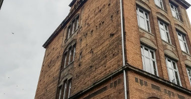 zdjęcie przedstawia budynek z perspektywy osoby stojącej pod nim patrzącej w górę na rogu
