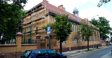 zdjęcie przedstawia budynek widziany od strony ulicy, na jednj ze ścian widać rusztowanie